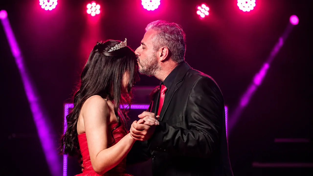 Debutante dançando com o pai sob iluminação cênica em festa de 15 anos
